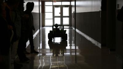 Micah taking his first ride in his toy ride-on car down the hallway at Southeast Tech