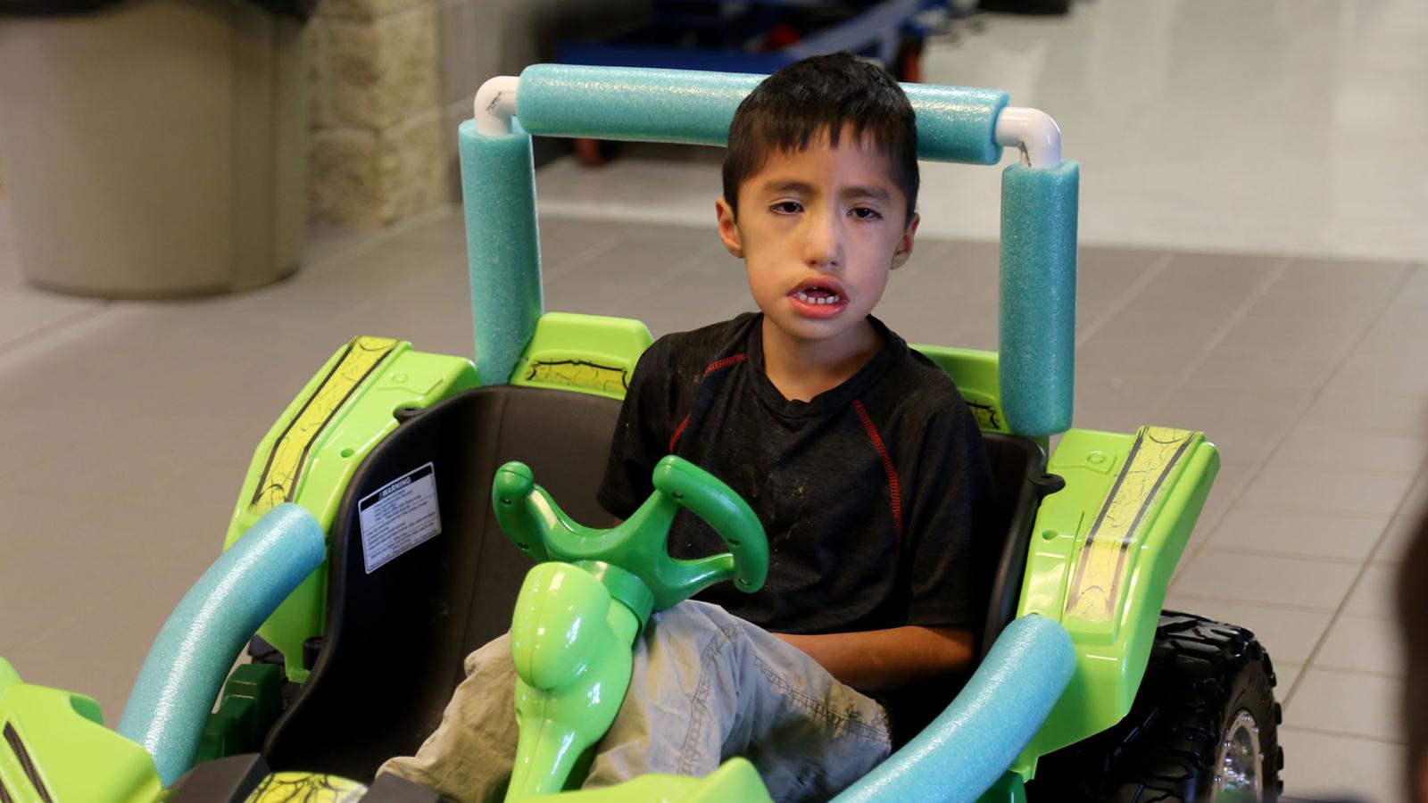 Micah smiling while sitting in his new modified toy ride-in car