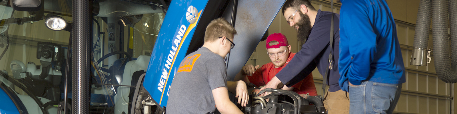 Group of students looking at engine under hood of tractor