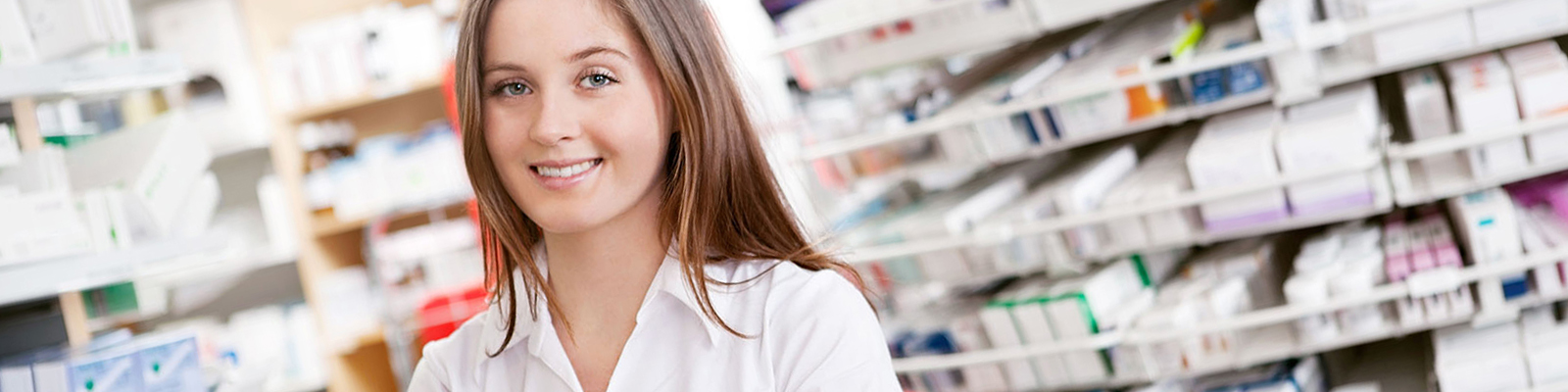 Young woman in posing in a pharmacy in front of rows of pills