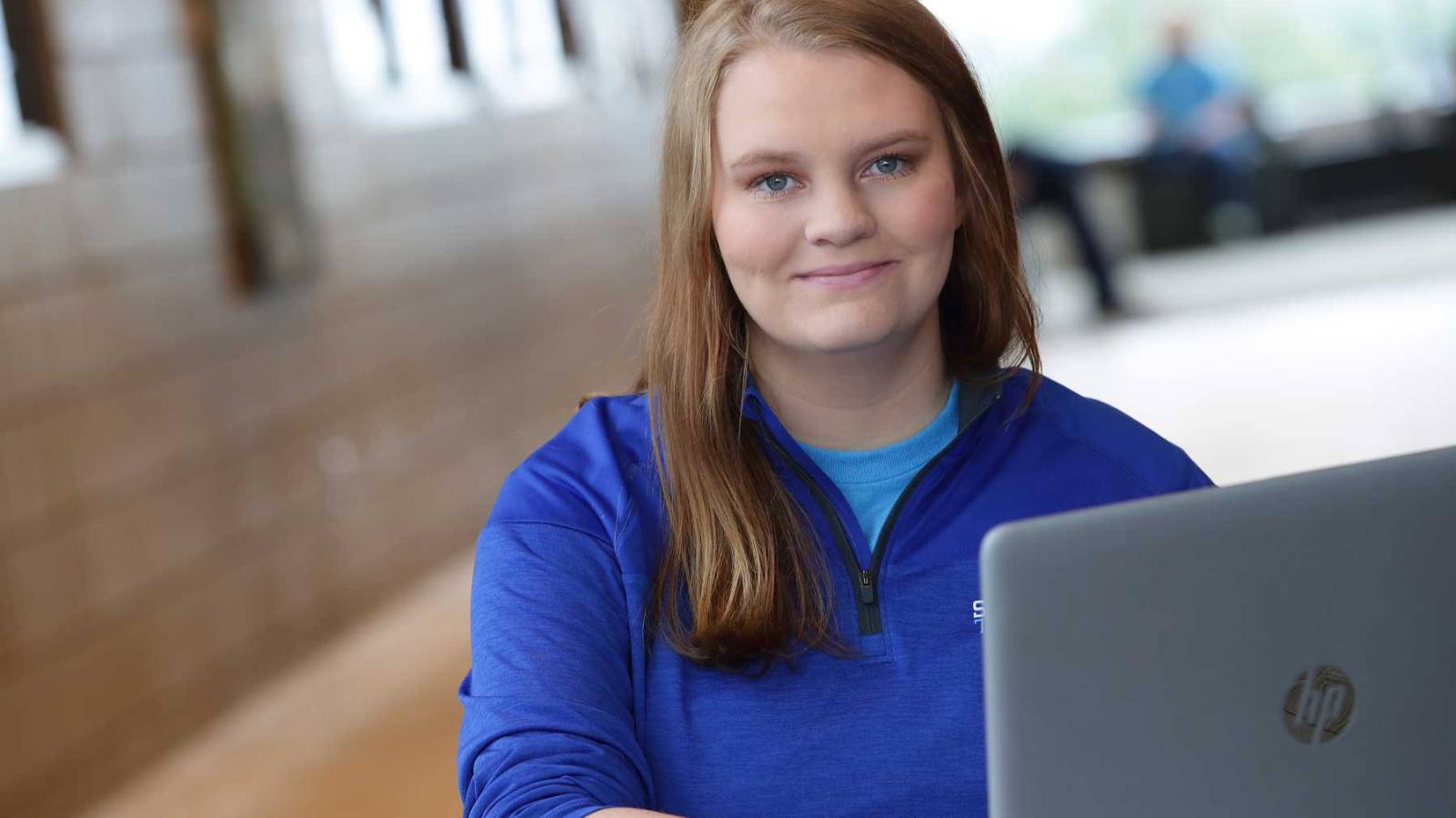 Female student working on laptop, smiling