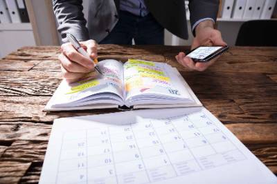 Man with open calendar, planner and smartphone at desk