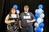 Student and parent on platform with black background and blue, white and silver balloons. 