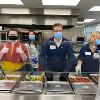 STC volunteers stand with President Griggs at serving line to help serve evening meal at The Banquet.